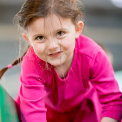 An elementary age girl playing on an obstacle course at recess or daycare.