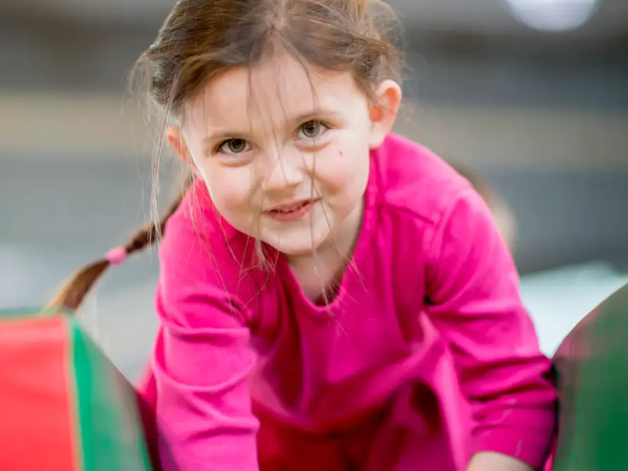 An elementary age girl playing on an obstacle course at recess or daycare.