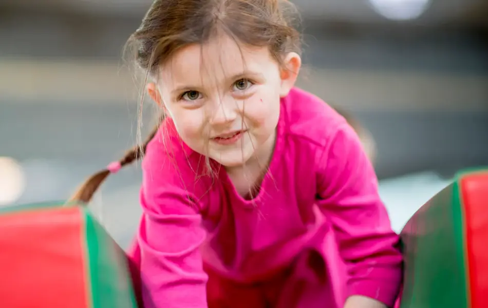 An elementary age girl playing on an obstacle course at recess or daycare.