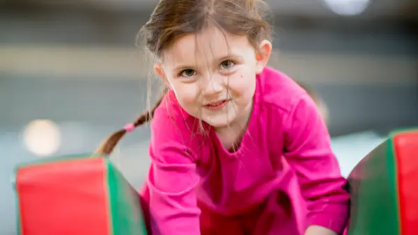 An elementary age girl playing on an obstacle course at recess or daycare.