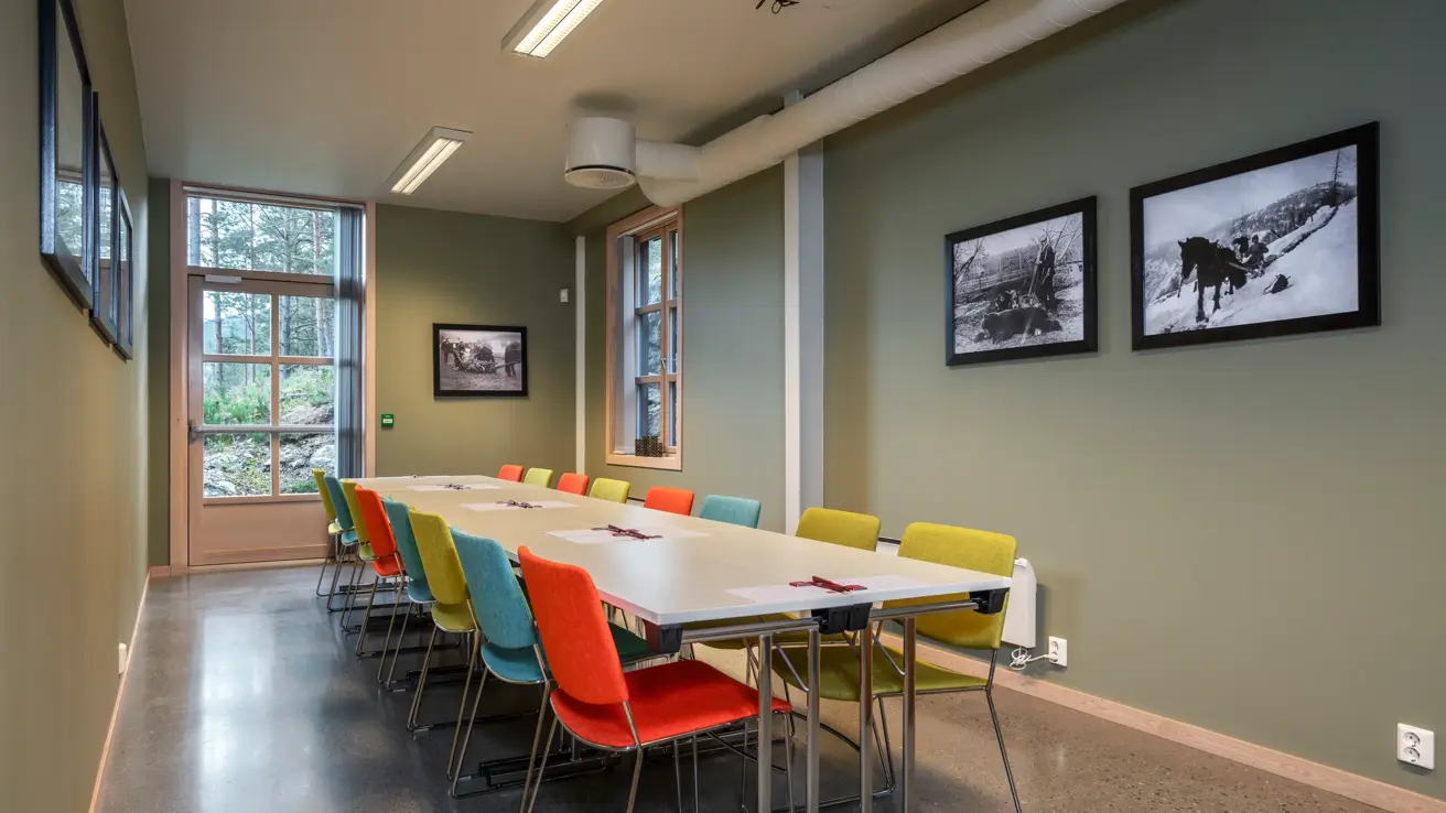 Møterom med styrebords oppsett, hvitt langbord og fargerike stoler