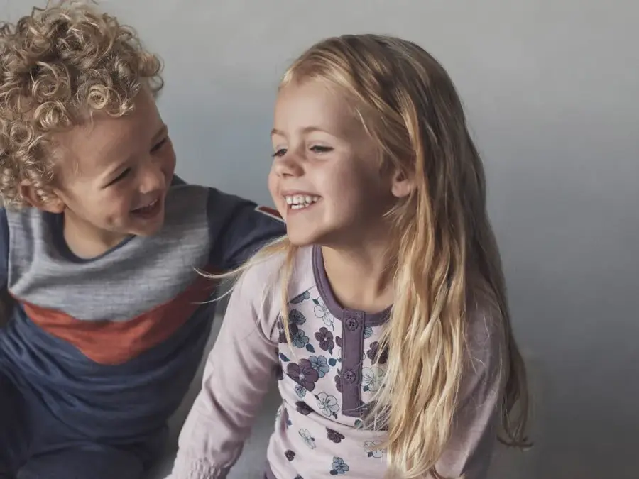 En gutt og en pike i barnehagealder som smiler og ler