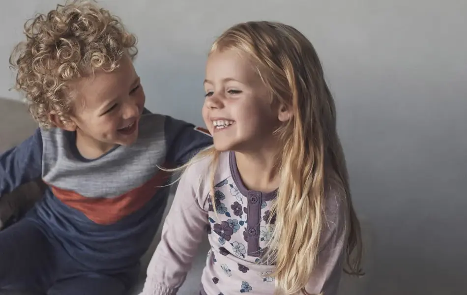 En gutt og en pike i barnehagealder som smiler og ler