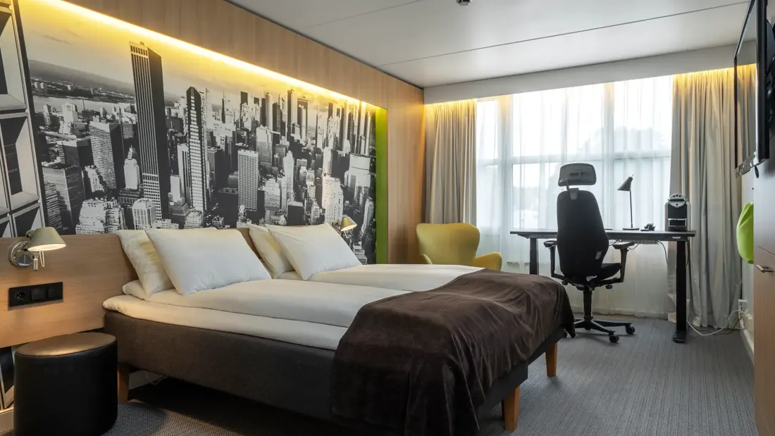 Dobbeltseng, vindu, skrivebord, skrivebordstol, TV, beige gardiner