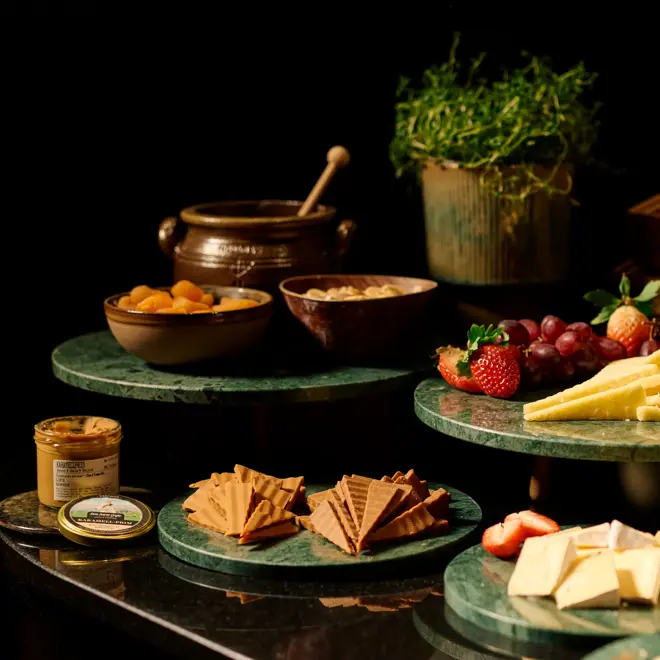 Forskjellige oster utstilt på runde grønne marmor fat på en frokostbuffet