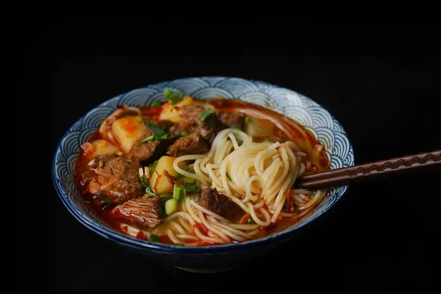 en bolle med ramen nudler, kjøtt og grønnsaker med et sett spisepinner
