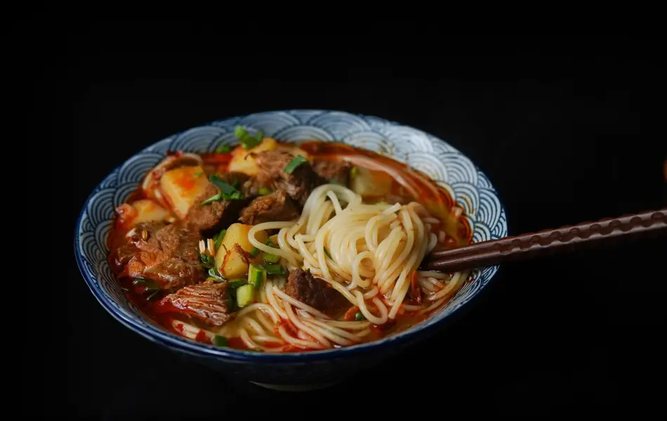 en bolle med ramen nudler, kjøtt og grønnsaker med et sett spisepinner