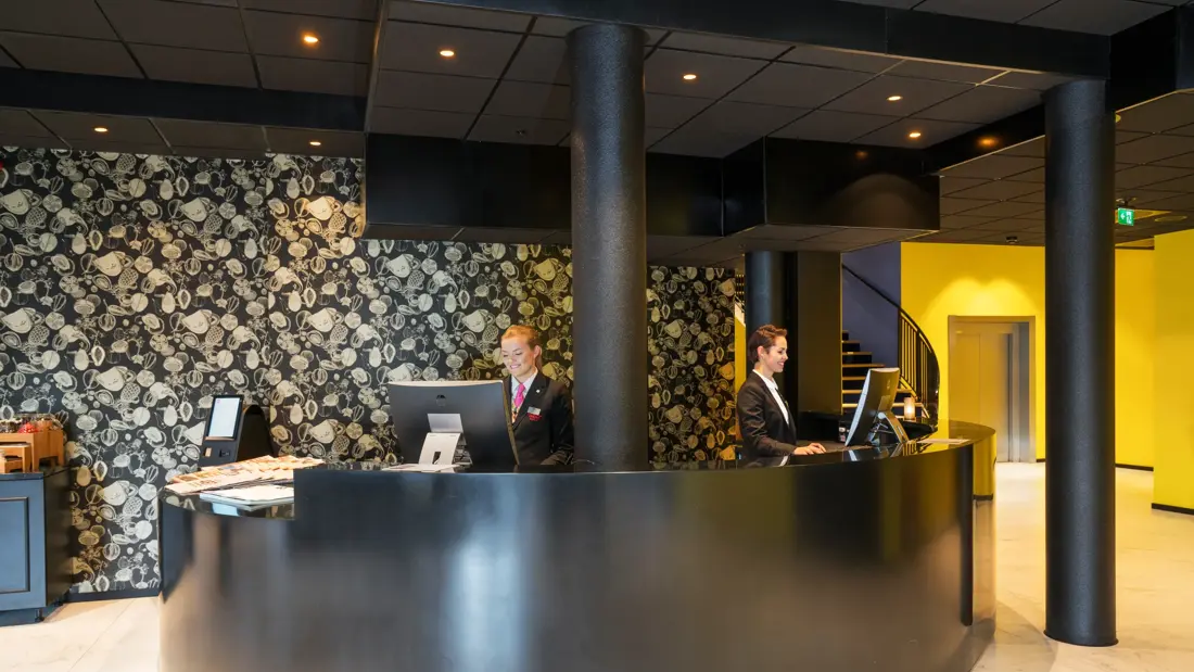 resepsjon med to ansatte med fin tapet i bakgrunnen på Thon Hotel Spectrum i Oslo sentrum
