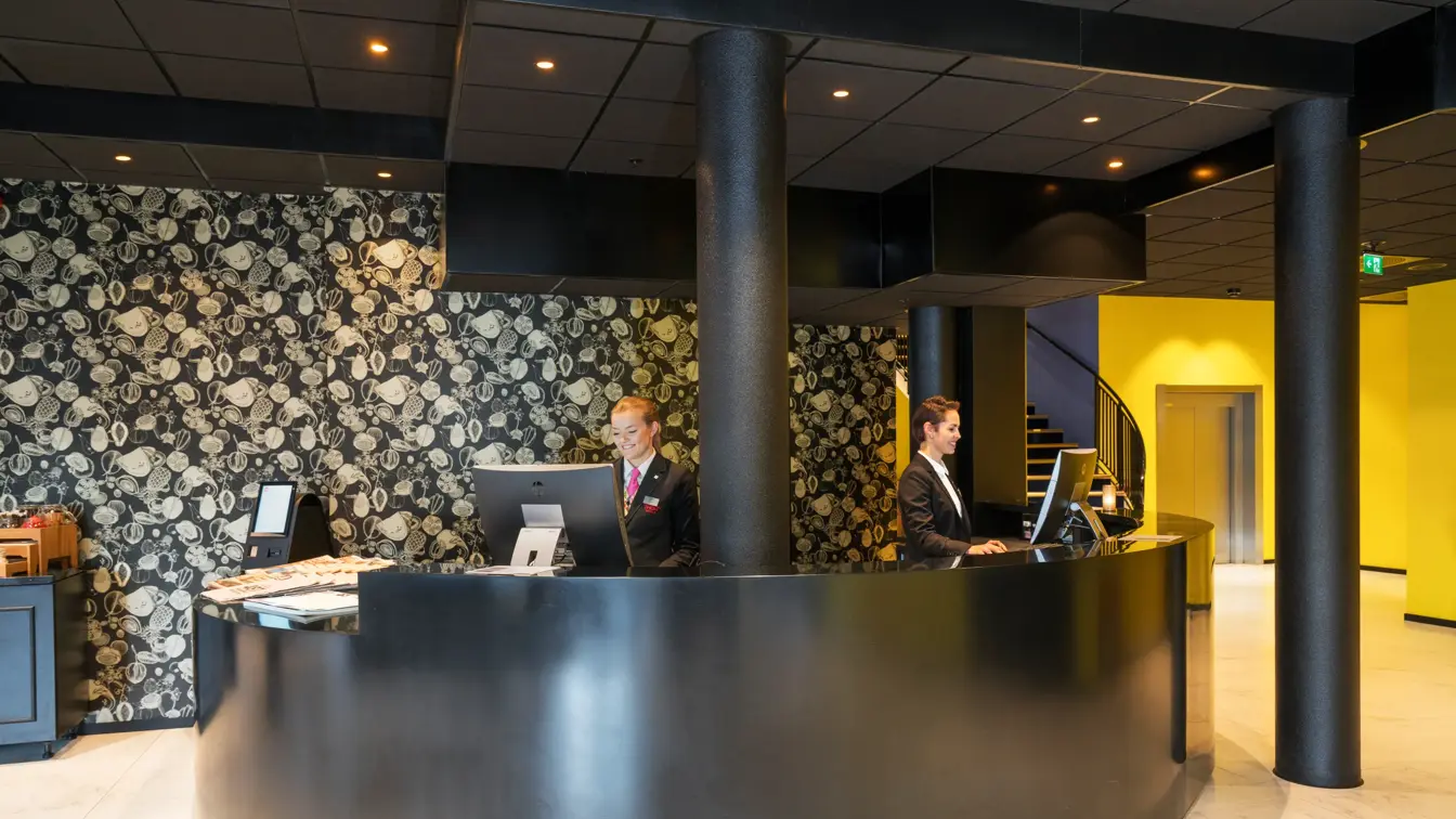 resepsjon med to ansatte med fin tapet i bakgrunnen på Thon Hotel Spectrum i Oslo sentrum