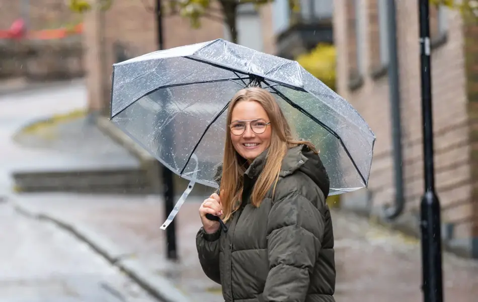 kvinne som krysser veien med paraply