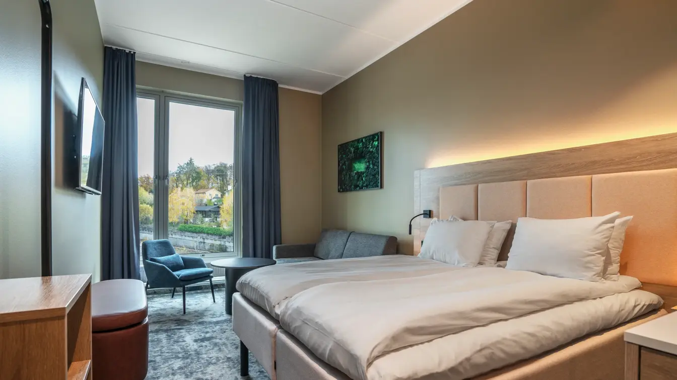 Dobbeltrom med dobbeltseng, sittegruppe, stort vindu med utsikt og vegghengt TV