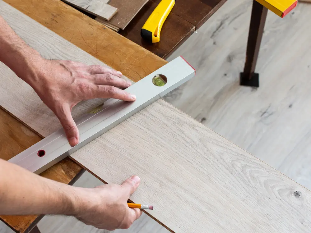 Installation laminate or parquet in the room, worker installing wooden laminate flooring, marking the length of the laminate