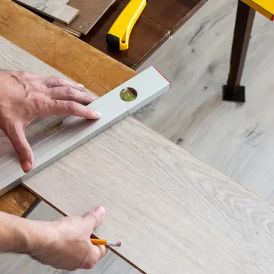 Installation laminate or parquet in the room, worker installing wooden laminate flooring, marking the length of the laminate