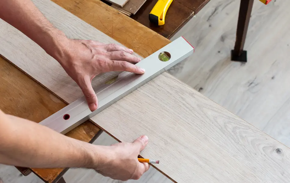 Installation laminate or parquet in the room, worker installing wooden laminate flooring, marking the length of the laminate