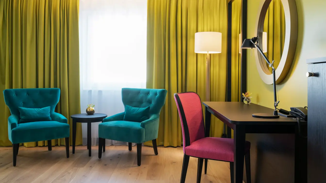 To lenestoler med ett bord. Skrivepult med stol. i Superior room med rosetapet på Thon Hotel Arendal i Arendal sentrum