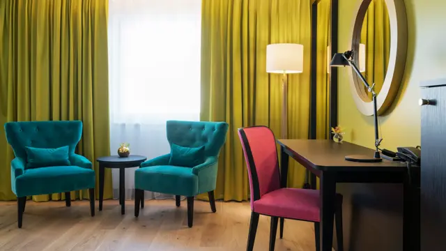 To lenestoler med ett bord. Skrivepult med stol. i Superior room med rosetapet på Thon Hotel Arendal i Arendal sentrum