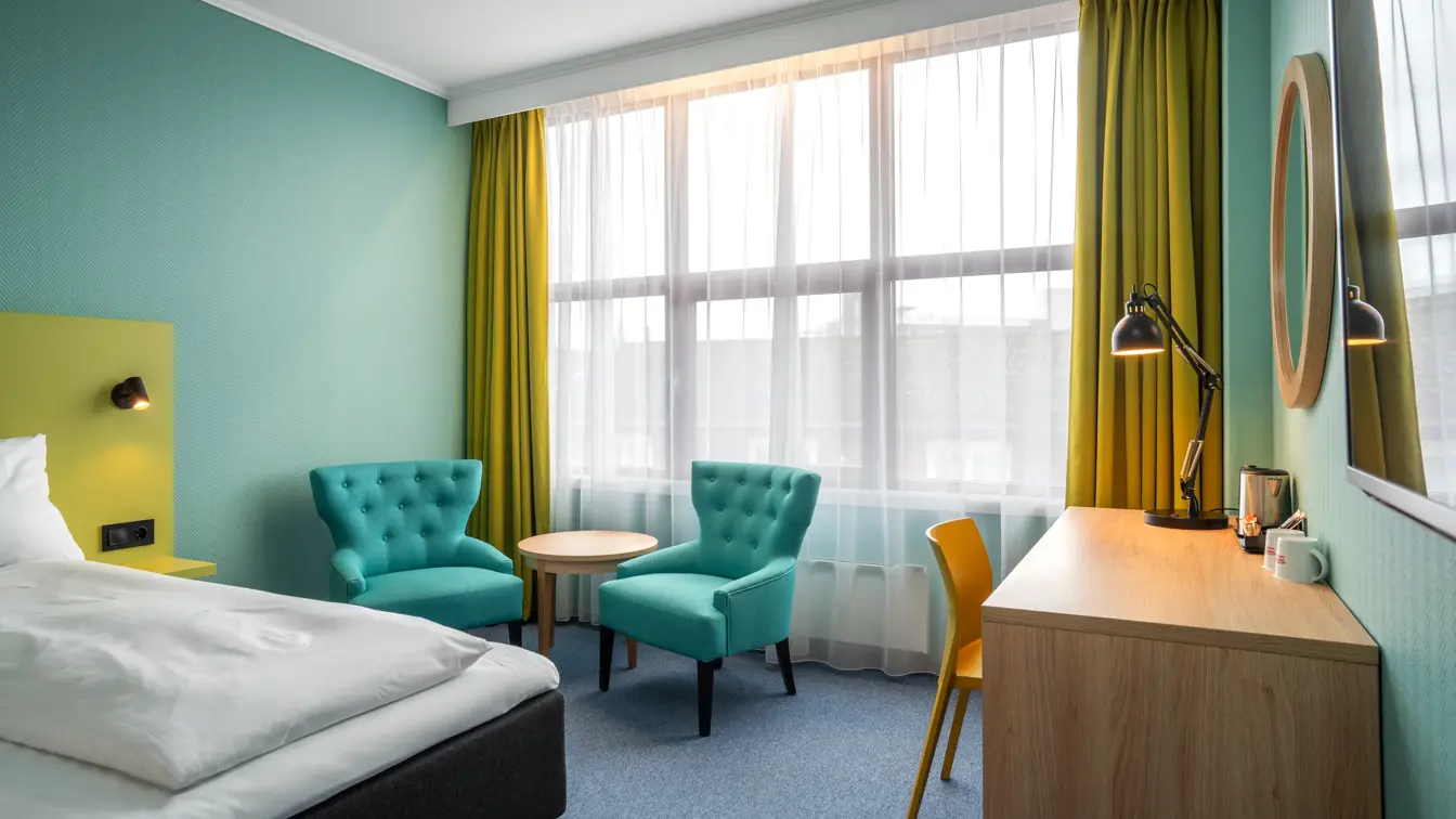 Vindu, gule gardiner, to turkise lenestoler, skrivebord, speil, twin beds, gul stol, turkise vegger