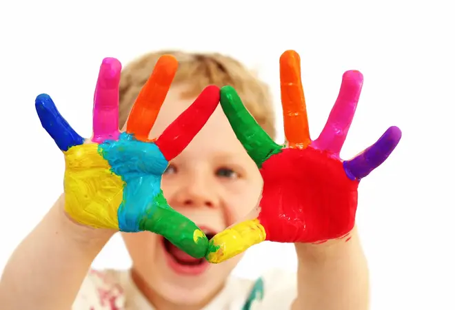 Five year old boy with hands painted in colorful paints ready for hand prints