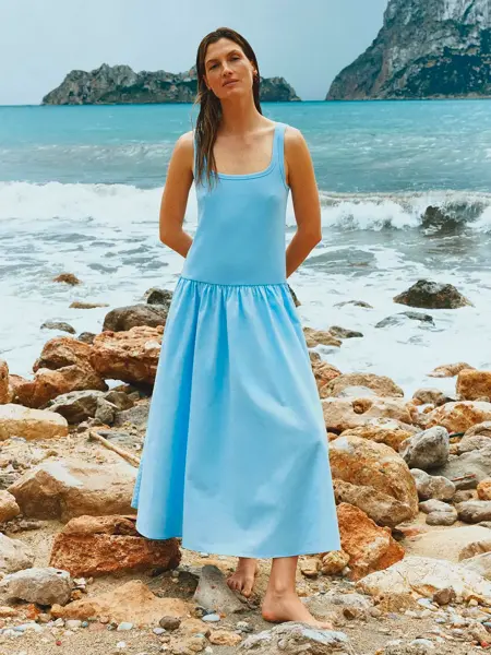 Dame på stranden i blå kjole. 