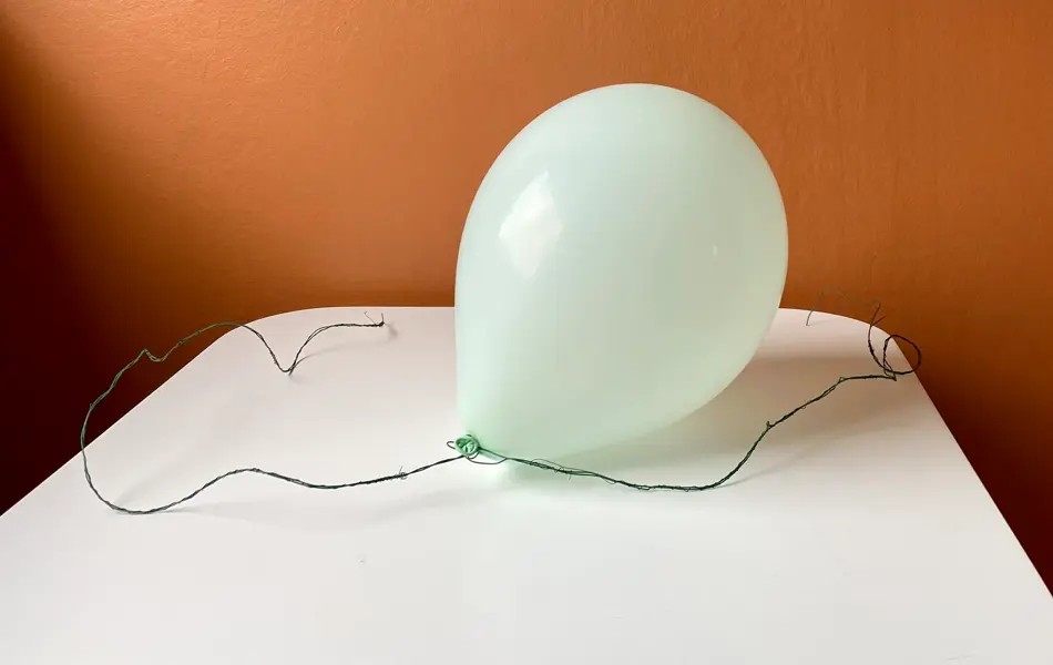 Oppblåst ballong med tråd som ligger på et bord med oransje bakgrunn