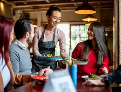 dame serverer mat til bord med tre personer