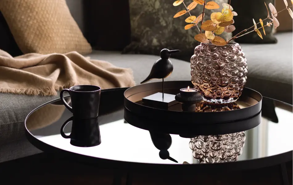 Sofa med bord dekket med vase med en kvist