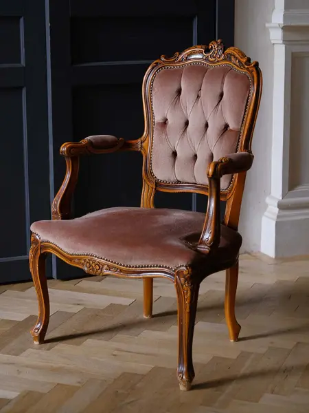 Antikk stol i barokk stil med bølgende tre og mørke, gammelrosa puter. Interiørtrend vår 2022.
