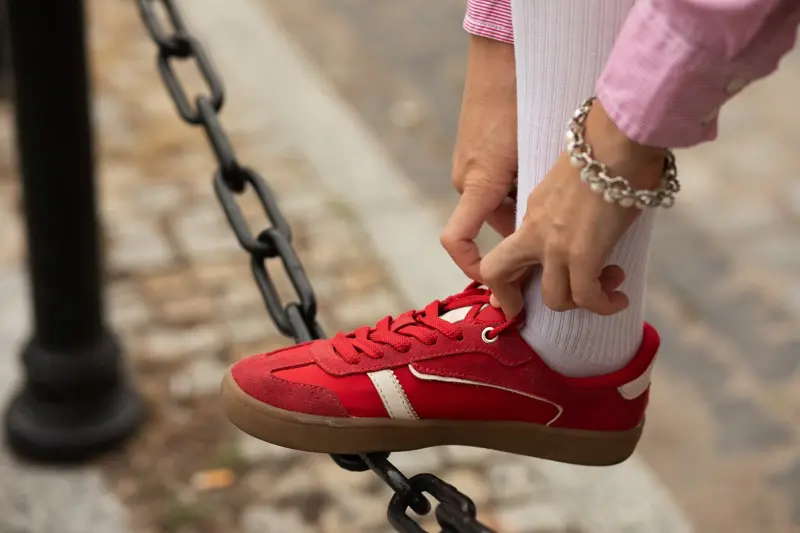 Nærbilde av damehender som knyter lisser på røde joggesko 