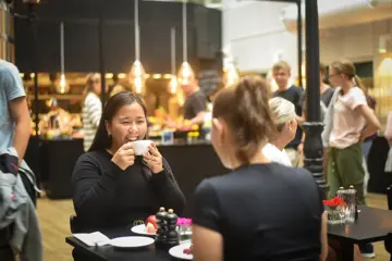 En jente spiser frokost og smiler til venninnen sin