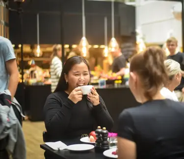En jente spiser frokost og smiler til venninnen sin