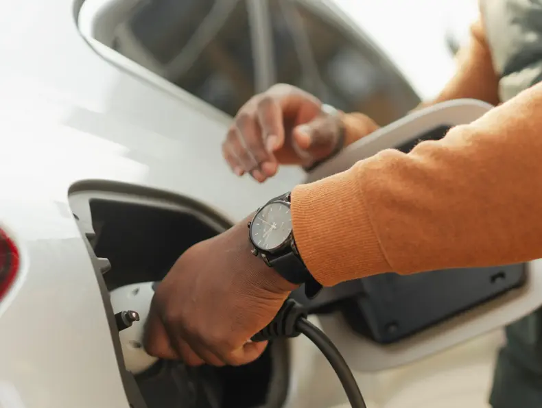 Nærbilde av ung mann som lader elektrisk bil