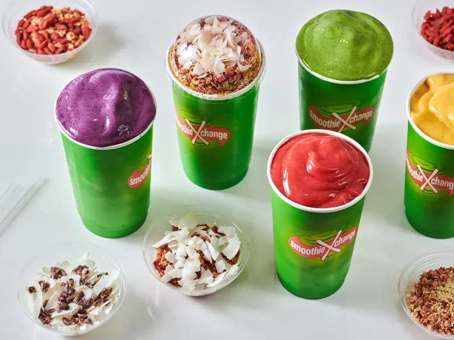 Fem smoothier i grønne beger med shavings ved siden av