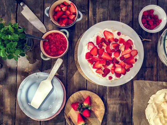Delicious Berry Pavlova Cake with fresh strawberries, raspberries, mint leaves and whipped cream.