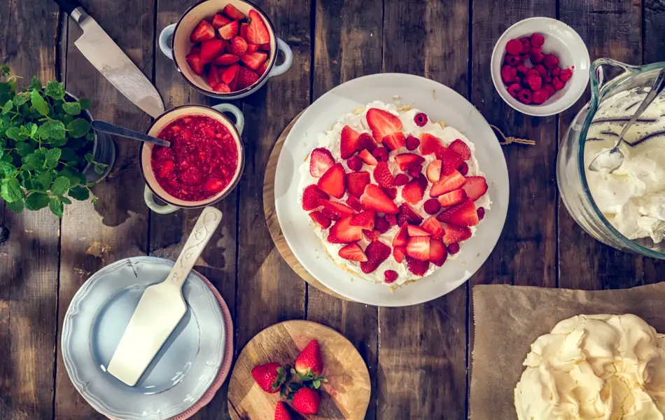 Delicious Berry Pavlova Cake with fresh strawberries, raspberries, mint leaves and whipped cream.