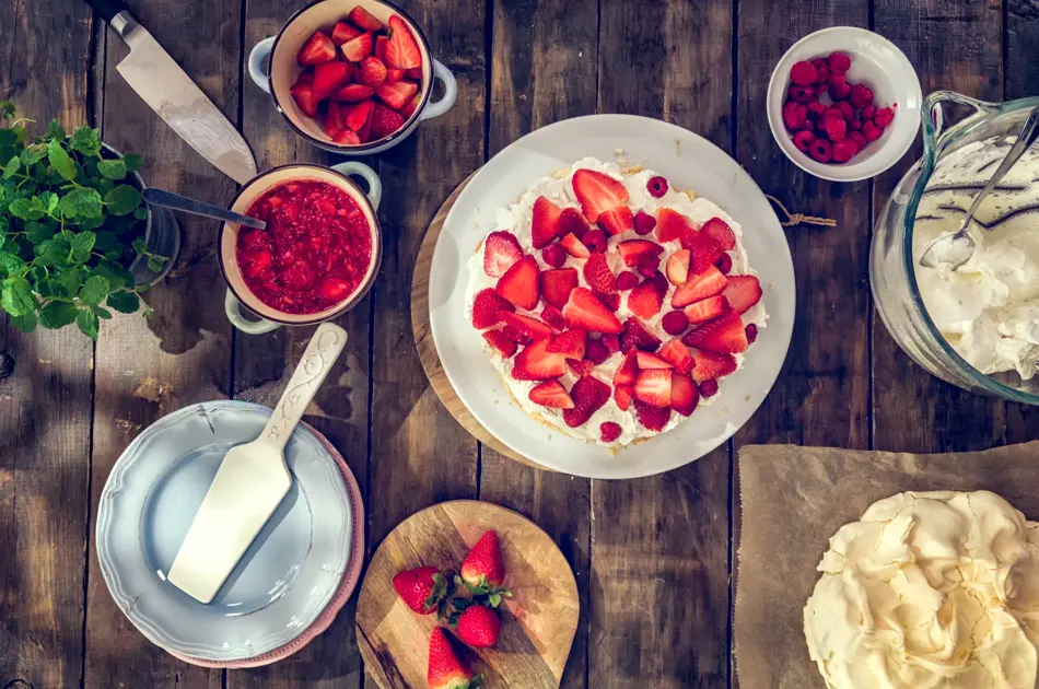 Delicious Berry Pavlova Cake with fresh strawberries, raspberries, mint leaves and whipped cream.