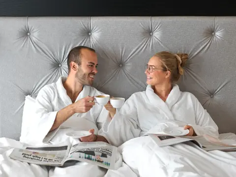 Kjærestepar, hotellseng, kaffe