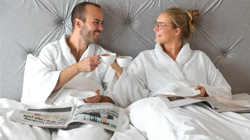 Kjærestepar, hotellseng, kaffe