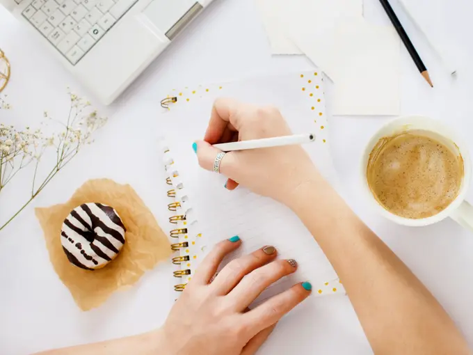 To hender som skriver i en notatbok