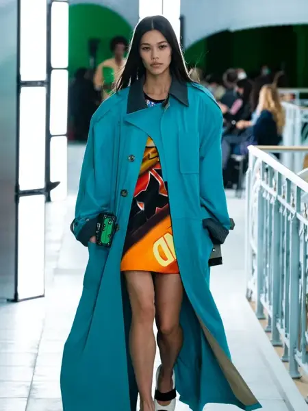 Dame på catwalk med en blågrønn trench