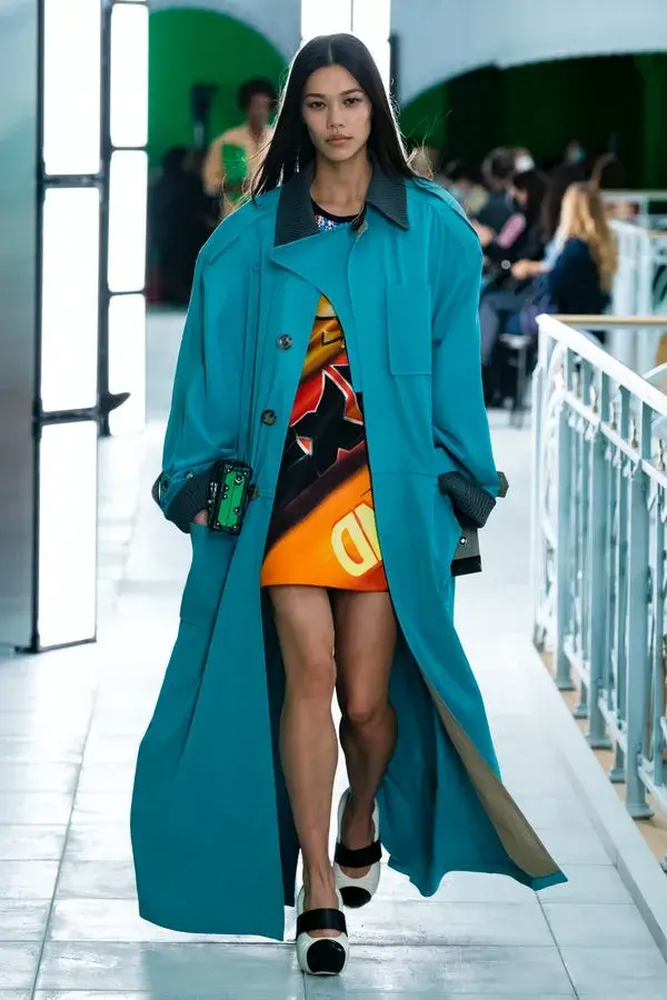 Dame på catwalk med en blågrønn trench