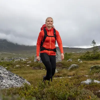 dame med rød jakke som er ute på tur i villmarken