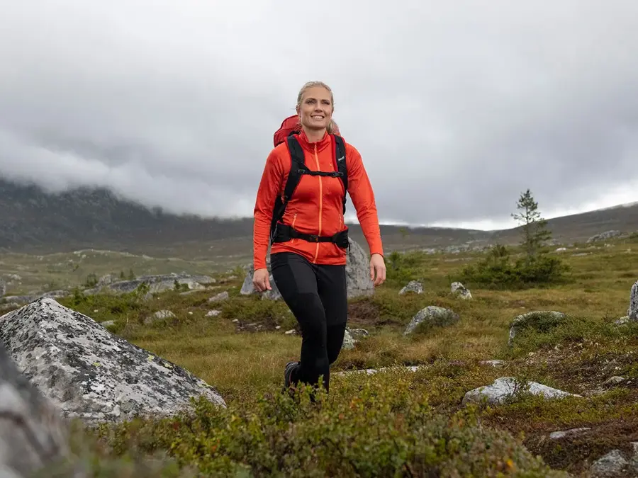dame med rød jakke som er ute på tur i villmarken
