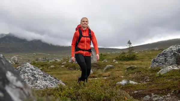 dame med rød jakke som er ute på tur i villmarken