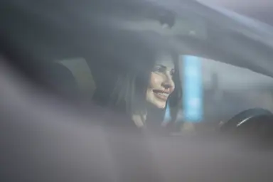 En kvinne som sitter i bilen og ser ut av vinduet.
