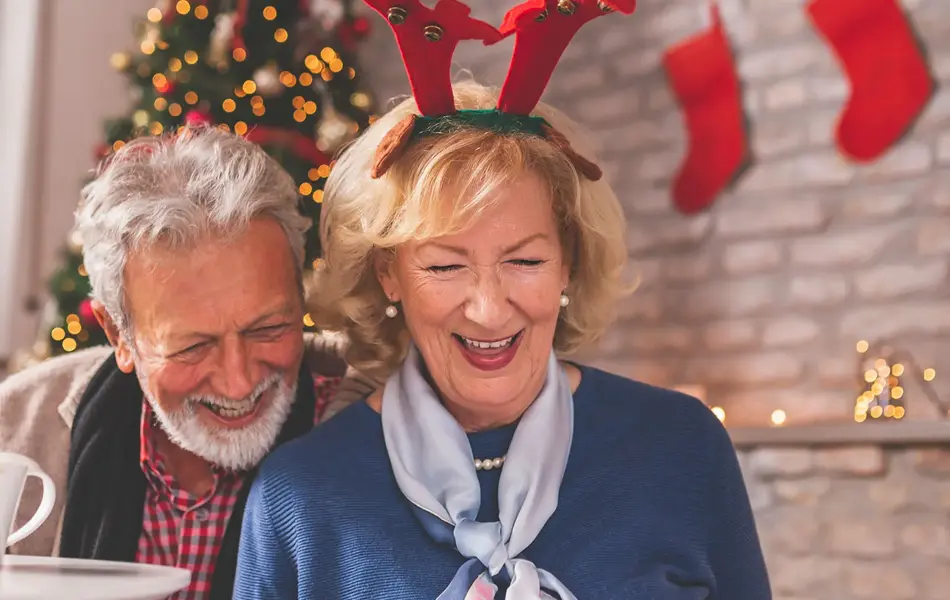 eldre mann og dame som ser på fotoalbum med juletre i bakgrunnen