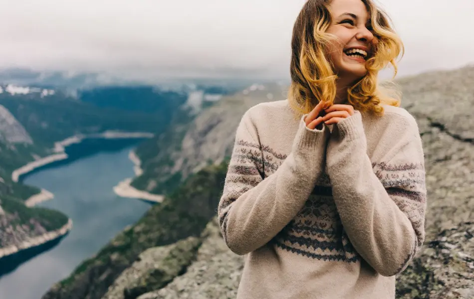 Girl standing on the Trolltunga and laughing 
