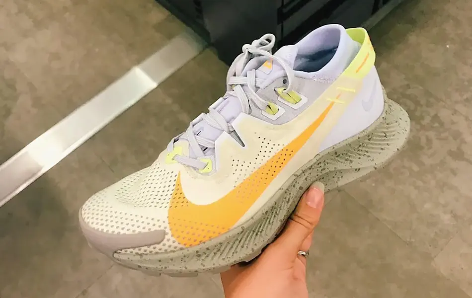 Nærbilde av en joggesko som blir holdt opp av en hånd