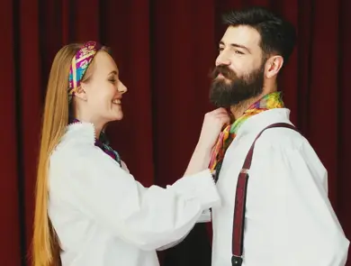 Bilde av dame som hjelper mann med å knytte bunadstørkle i halsen