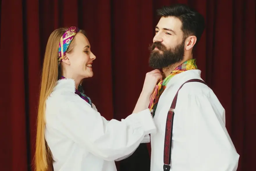 Bilde av dame som hjelper mann med å knytte bunadstørkle i halsen