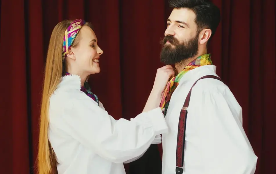 Bilde av dame som hjelper mann med å knytte bunadstørkle i halsen